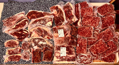 1/8 vacuum-sealed packs of grass-fed beef cuts and ground beef from Diamond D Ranch displayed on a patterned surface.