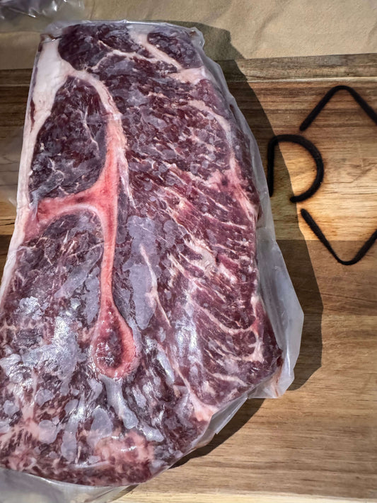 A well-marbled roast beef steak rests on a wooden cutting board, highlighting its rich texture and fat distribution, suggesting freshness and flavor.