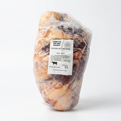 A large raw beef heart packaged in clear plastic wrap with a white label