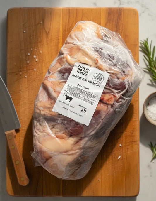 The healthiest beef cuts, vacuum-sealed beef heart on the chopping board with knife, salt, and herbs from Diamond D Ranch.