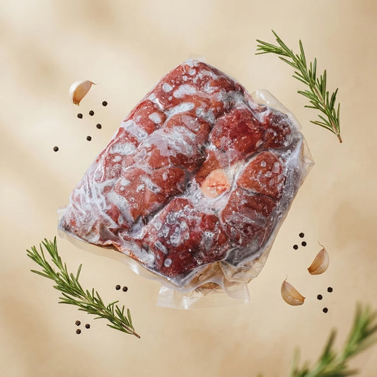 Flash-Frozen Beef Kidney in a clear vacuum-sealed bag, styled with garlic cloves, peppercorns, and rosemary sprigs on a warm beige background.