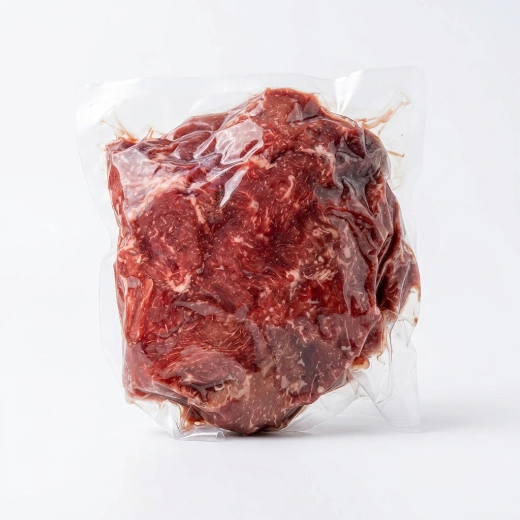 Beef stew meat chunks vacuum sealed in a clear pouch on a white background