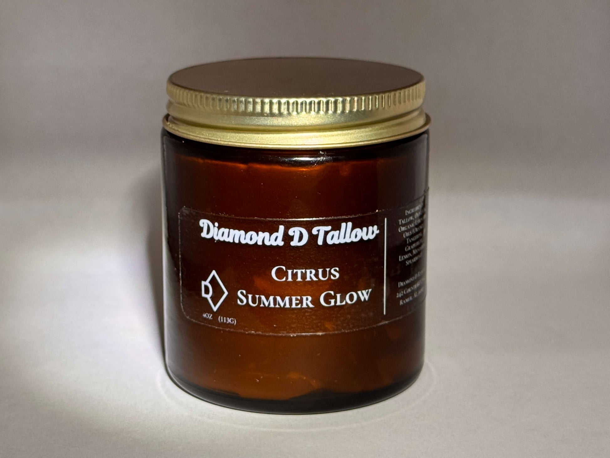 Amber jar with gold lid labeled "Diamond D Tallow, Citrus Summer Glow." The product exudes a simple, elegant, refreshing vibe.