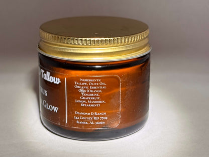 A brown glass jar with a gold lid labeled "Tallow Citrus Glow." Ingredients like tallow, olive oil, and essential oils are listed. Simple, earthy tone.