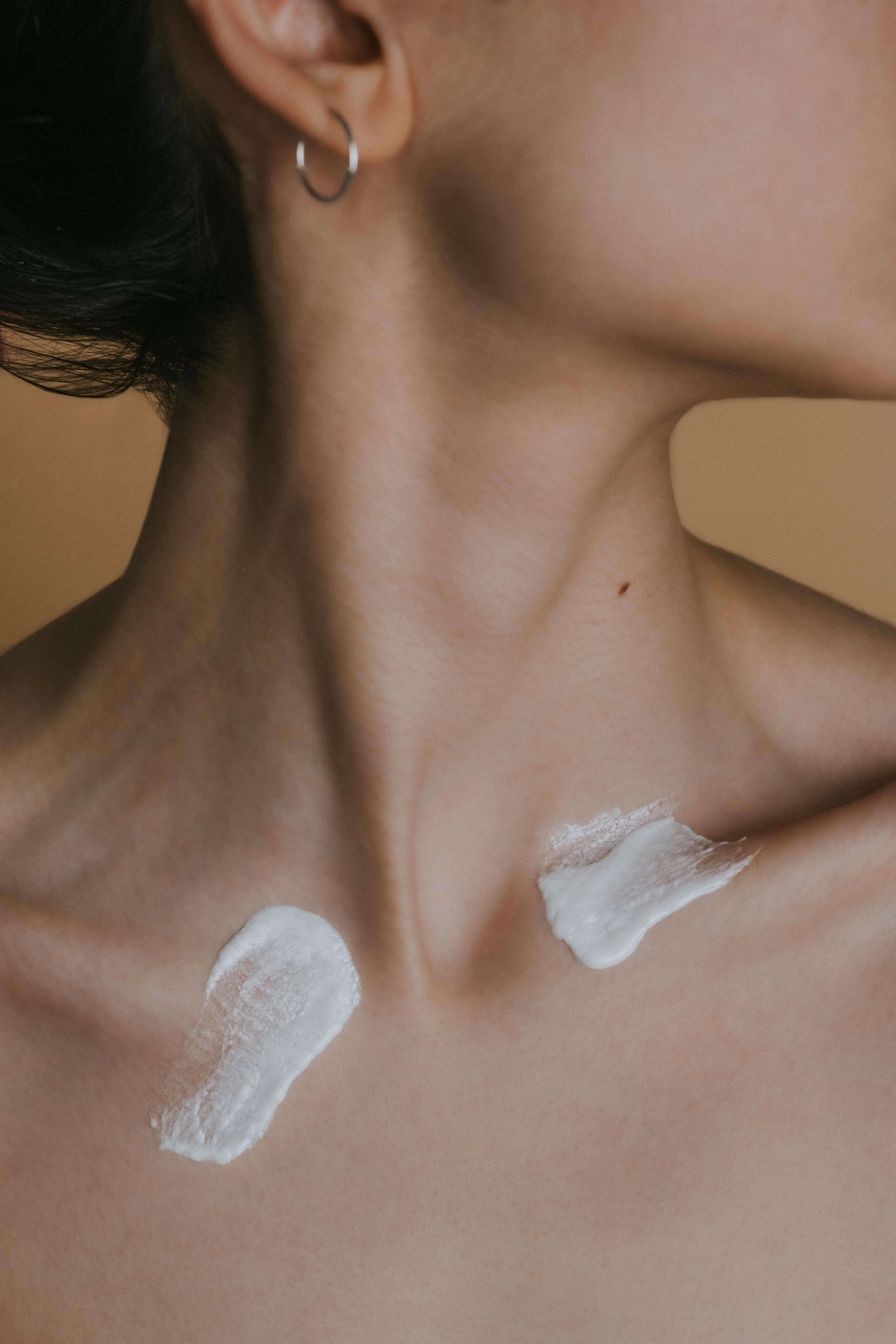 Close-up of a woman's neck and collarbone with whipped tallow. Her head is turned to the side, displaying an elegant and serene mood.