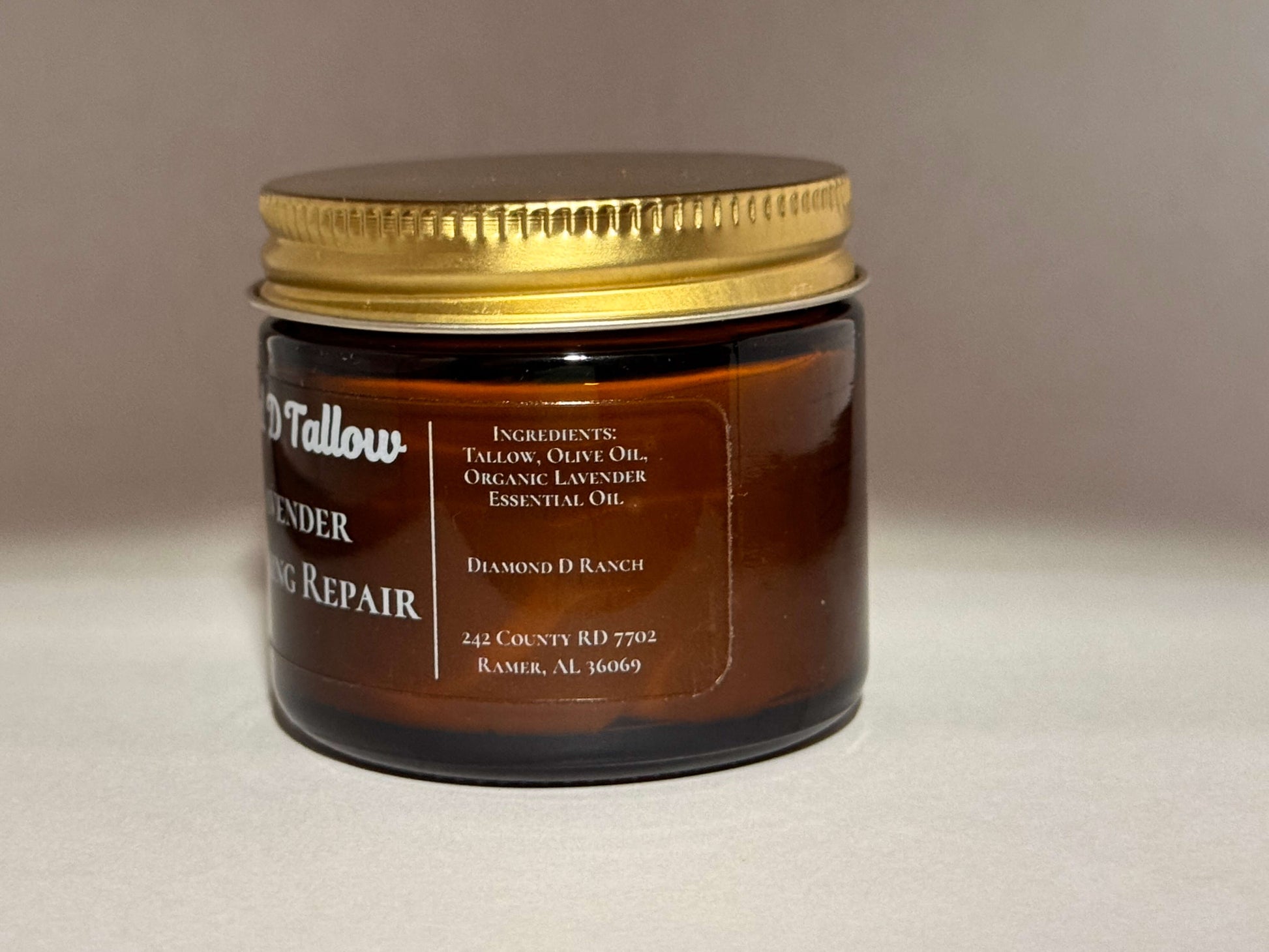 Brown glass jar with a golden lid labeled "Lavender Healing Repair" featuring ingredients like tallow, olive oil, and organic lavender essential oil. Cozy and natural vibe.