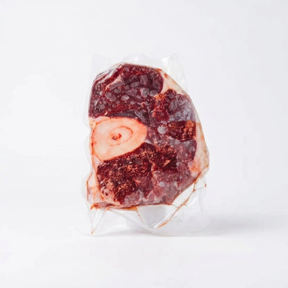 Raw osso buco cross cut with marrow bone, vacuum sealed on a white background