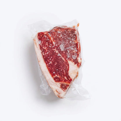 Sirloin steak vacuum sealed showing rich marbling and light frost on a white background
