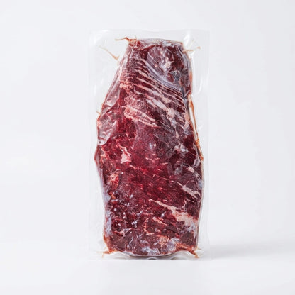 Long skirt steak in vacuum-sealed packaging on a plain white background