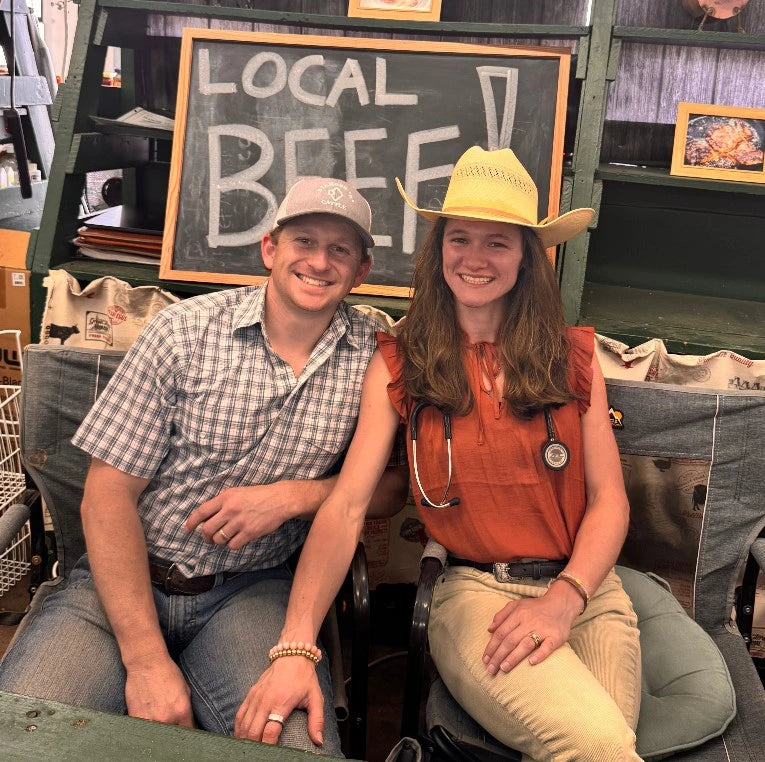 Dalton and Sydney sitting together with a chalkboard sign behind them that reads 'LOCAL BEEF'.