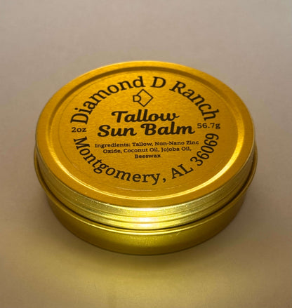 A gold tin labeled "Diamond D Ranch Tallow Sun Balm" with ingredients like tallow, zinc oxide, coconut and jojoba oils, beeswax; 56.7g; Montgomery, AL.