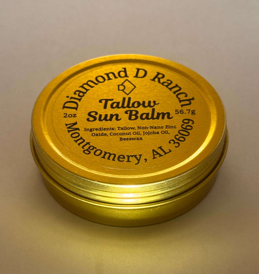 A gold tin labeled "Diamond D Ranch Tallow Sun Balm" with ingredients like tallow, zinc oxide, coconut and jojoba oils, beeswax; 56.7g; Montgomery, AL.